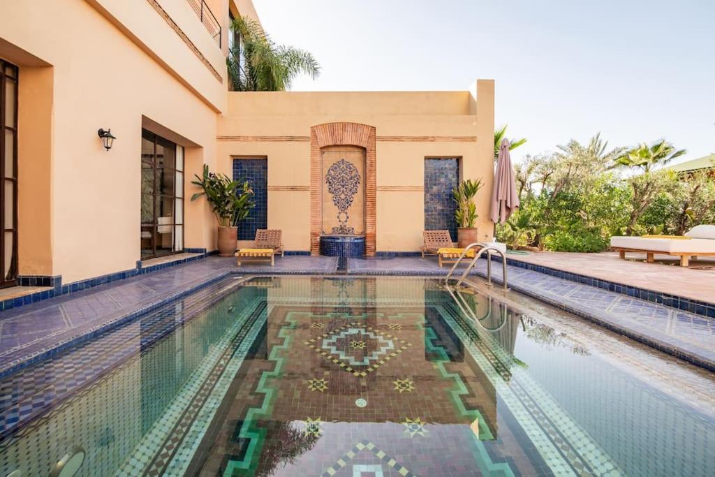 a villa with a swimming pool and a house at Villa May sur le Golf de la Palmeraie with Cooker and Butler included in Marrakech