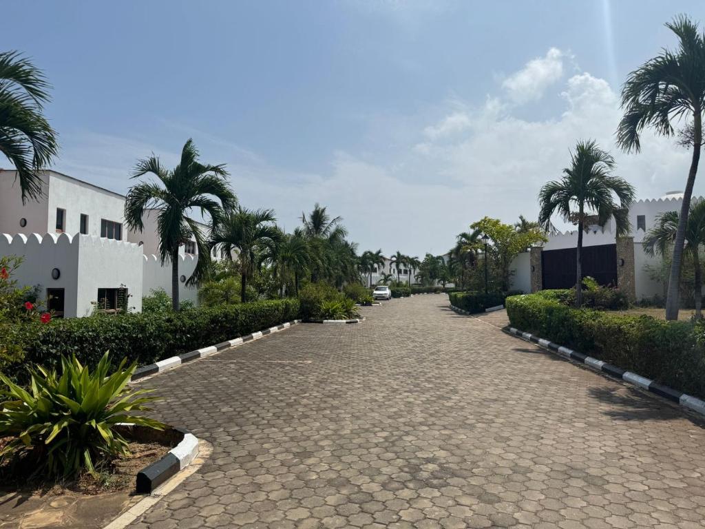 une rue pavée avec des palmiers et des bâtiments dans l'établissement Love Birds Palace, à Mombasa