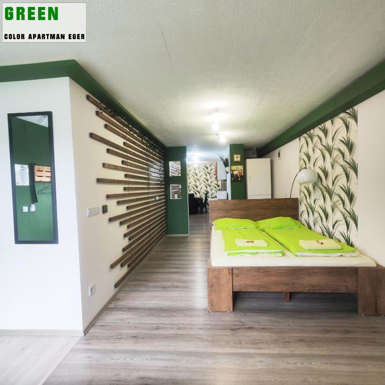 a bedroom with a bed with green pillows on it at Color Apartmanok Eger in Eger