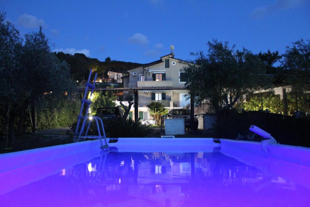 una piscina con illuminazione viola di fronte a una casa di Villa Carol a Santa Maria di Castellabate