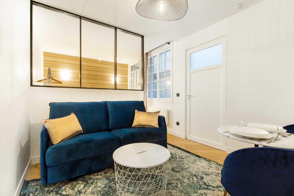 ein Wohnzimmer mit einem blauen Sofa und einem Tisch in der Unterkunft Chic Apartment in the Prestigious Saint Honoré in Paris