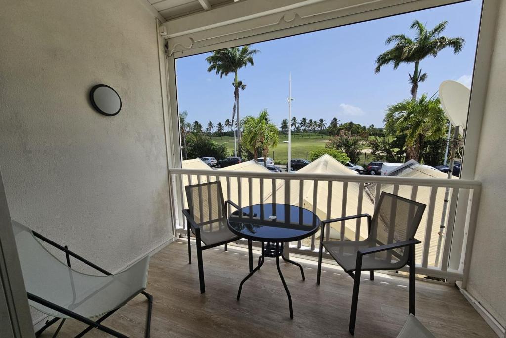 d&#39;un balcon avec une table, des chaises et des palmiers. dans l&#39;établissement Appartement Le Golfeur, à Saint-François