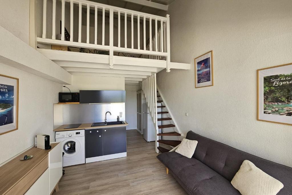 Il comprend un salon avec un canapé, une cuisine et un escalier. dans l&#39;établissement Appartement Le Golfeur, à Saint-François