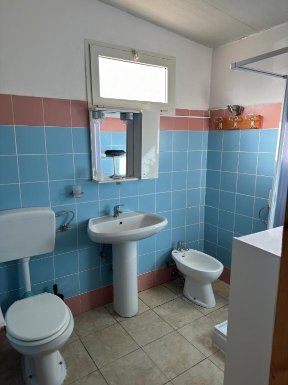 bagno piastrellato blu con servizi igienici e lavandino di Sunset Village a Marina di Montenero