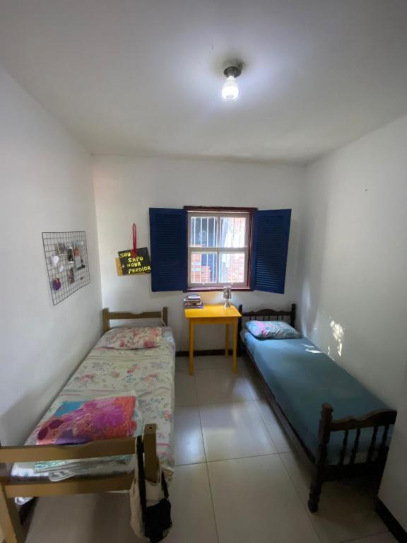 a bedroom with two beds and a table and a window at República Xamego in Ouro Preto