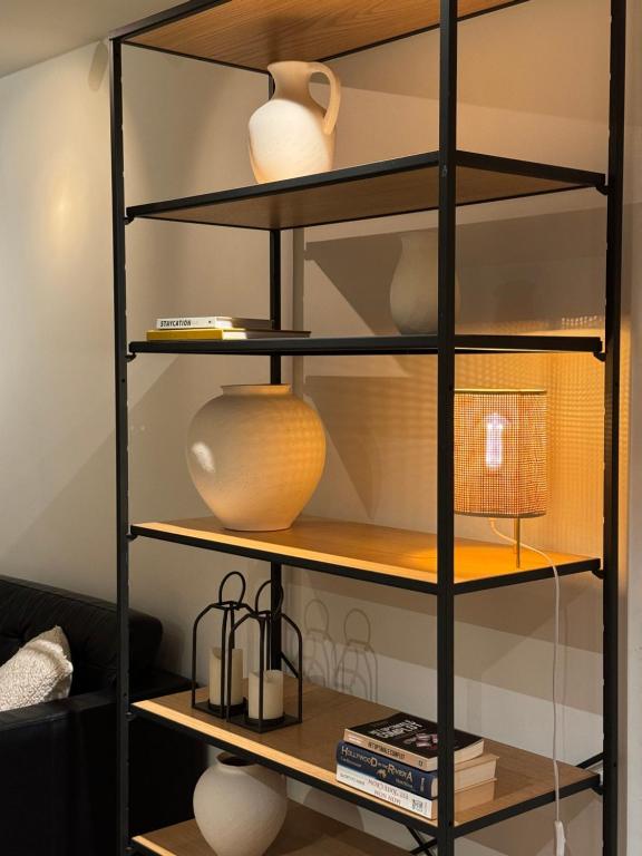 a black shelving unit with vases and a lamp at Luxury Apartment with Cosy Garden! in Ghent