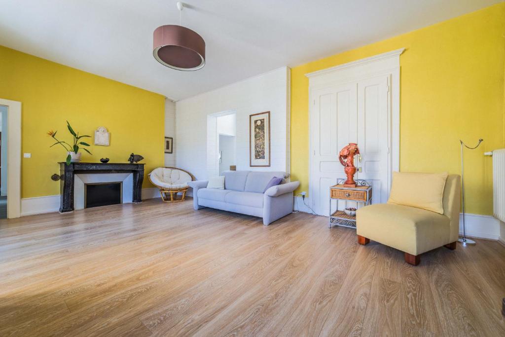 ein Wohnzimmer mit gelben Wänden, einem Sofa und Stühlen in der Unterkunft Maison cozy - 3 chambres - Tulle in Tulle