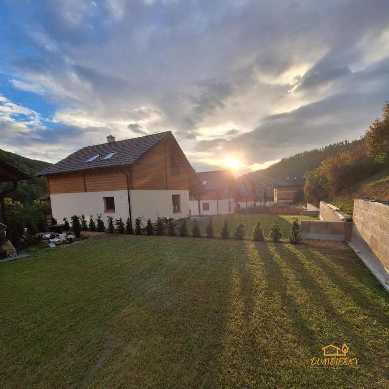 a house in a yard with the sunset in the background at Ďumbierky Chata 6ka in Mýto pod Ďumbierom