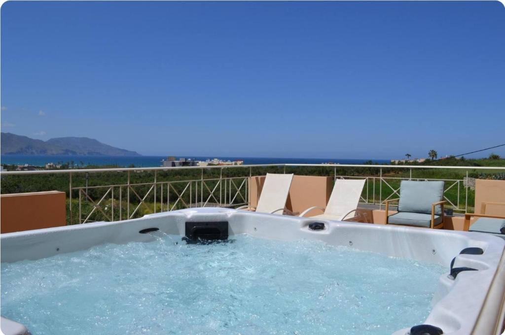 a jacuzzi tub on a patio with chairs at Villa Ydramia Seaview in Dhrámia