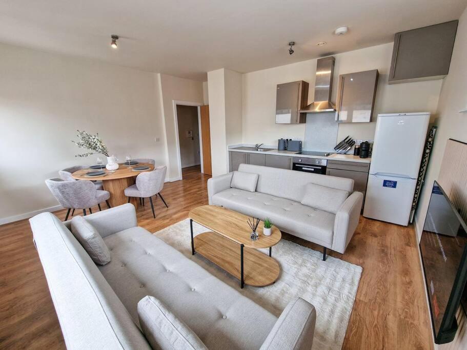 sala de estar con sofá, mesa y cocina en Free Parking Stunning City Centre Flat en Mánchester