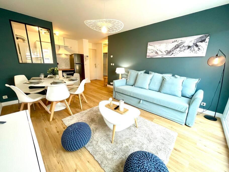 sala de estar con sofá azul y mesa en Le Familial - Terrasse - Proximité Genève, en Saint-Genis-Pouilly