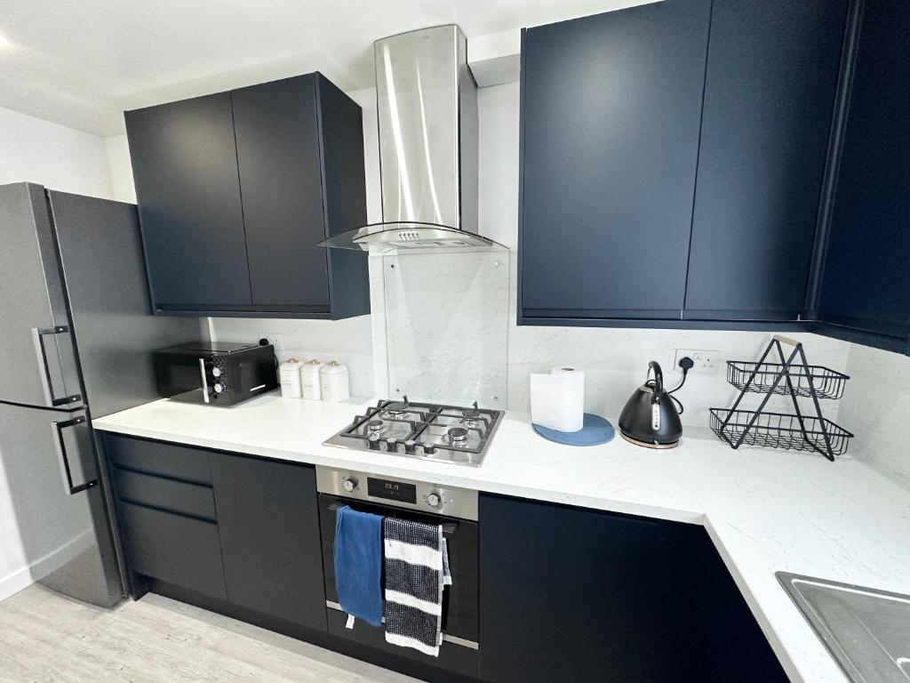 uma cozinha com armários pretos e um forno com placa de fogão em 3 Bedroom Home In London - Lee - By Atleys Homes em Londres