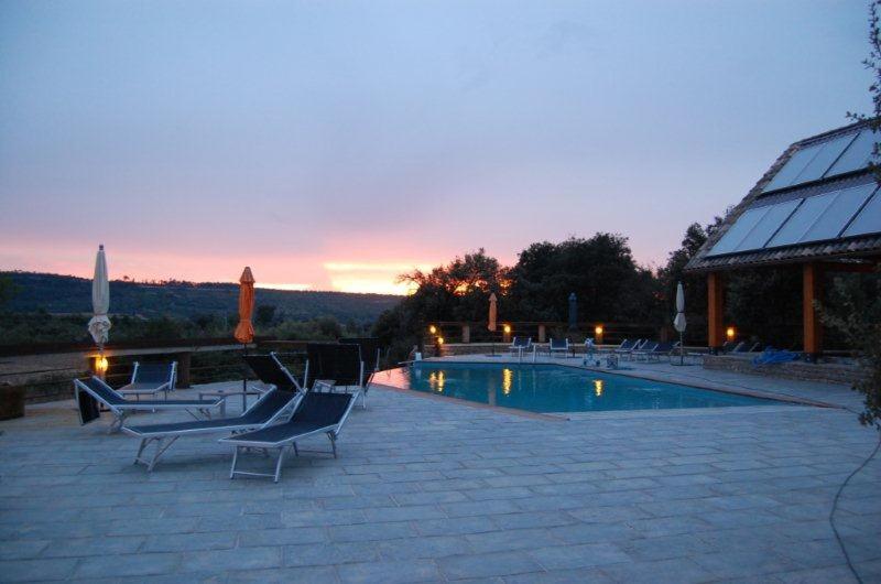 eine Terrasse mit Stühlen und ein Pool am Abend in der Unterkunft Hotel Villaro Del Bosc in Freixinet