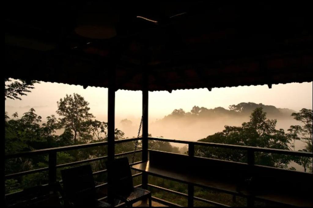 a room with a balcony with a view of a misty valley at Bhuvi Wayanad Natural Tea Plantation Resort in Wayanad