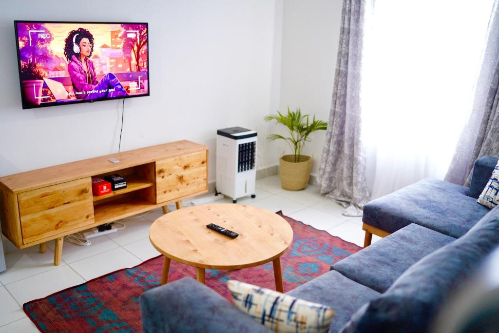 ein Wohnzimmer mit einem Sofa und einem TV an der Wand in der Unterkunft Serenity Haven, 1 BR, Pool, Wi-Fi, IPTV, Netflix, Air Conditioner in Mombasa