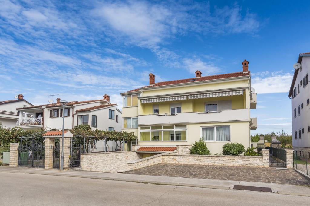 a yellow and white house on the side of a street at Alto Apartments in Umag