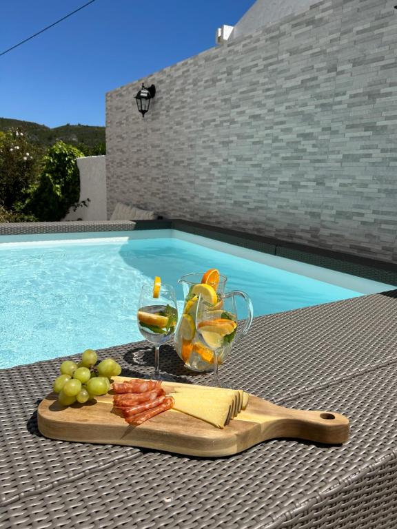 uma bandeja de frutas e um copo de vinho numa mesa junto à piscina em Vivenda Santiago em Sesimbra