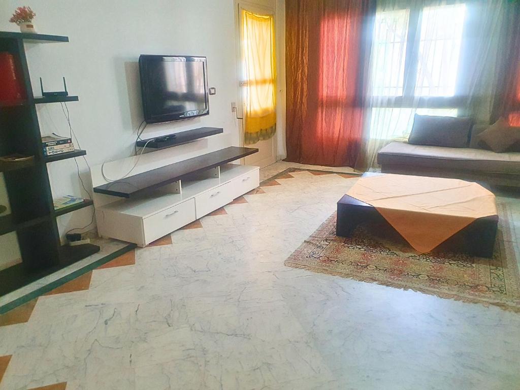 a living room with a couch and a tv at Duplex Familial 2 Chambres 131m2 avec Jardin Privé - Service Aéroport - Internet Fibre Optique in Burj at Turkī