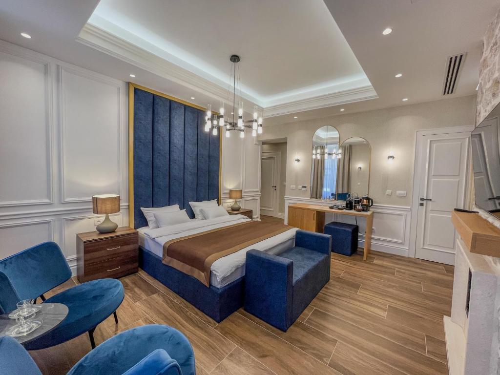 1 dormitorio con 1 cama extragrande y sillas azules en Hive Luxury Suites by MN Property, en Kotor