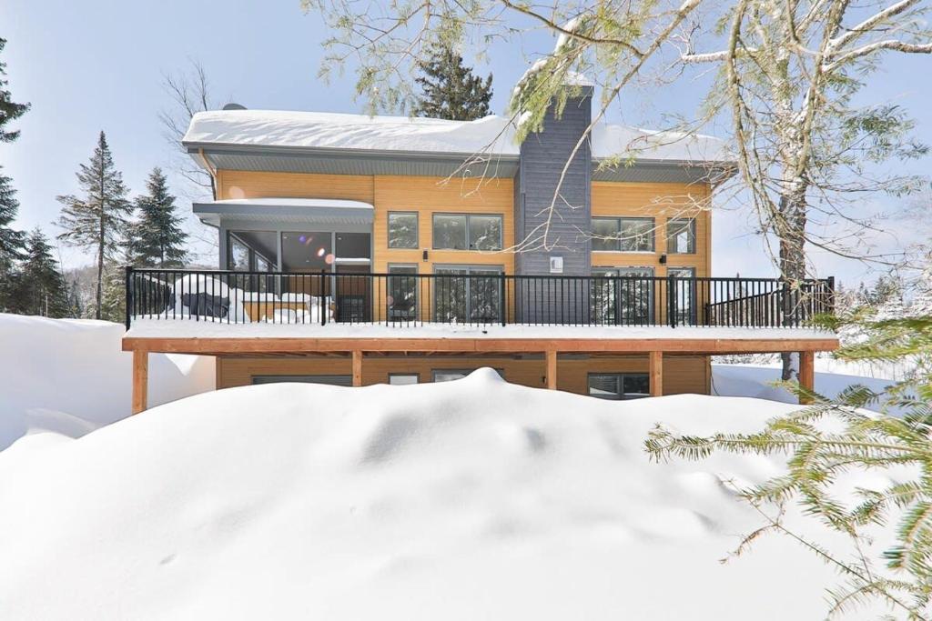 uma casa no inverno com neve em frente em Le Scandinave em Saint Adolphe D'Howard