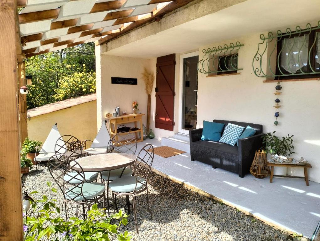 a patio with a table and chairs and a couch at Studio avec terrasse au calme in Hyères