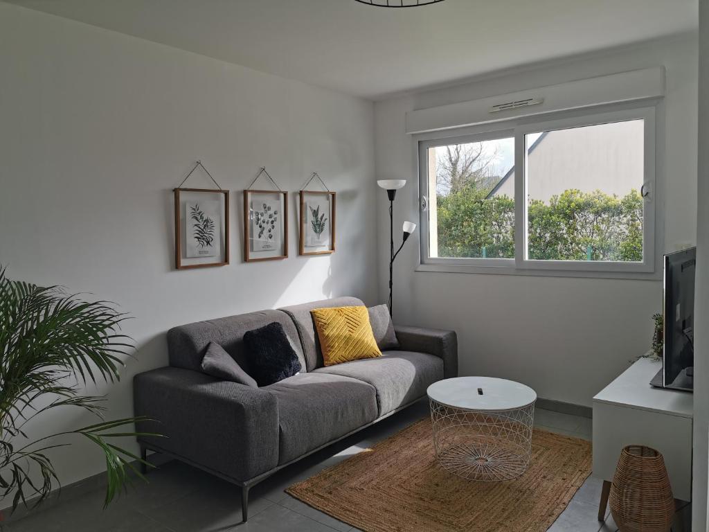 un salon avec un canapé et une fenêtre dans l'établissement Maison proche Bayeux, à Saint-Martin-des-Entrées