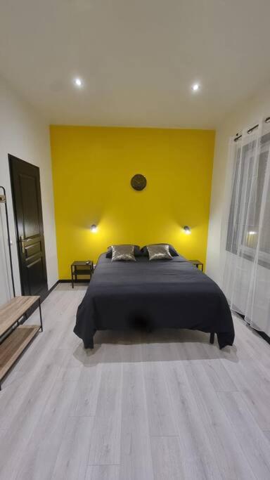 um quarto com uma cama com uma parede amarela em L'Elégance 001 em Cambrai