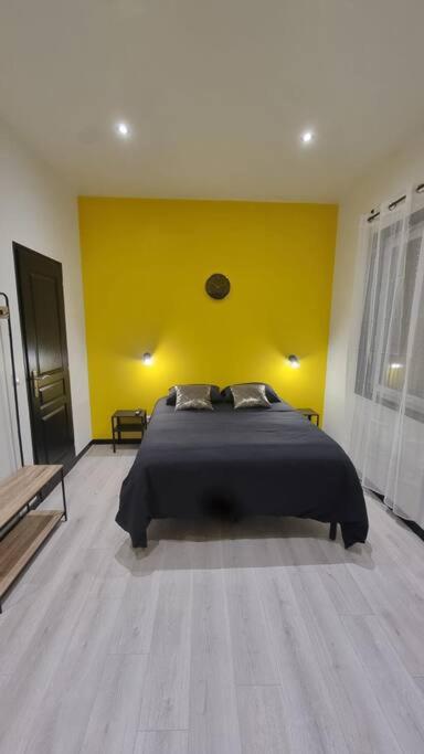 une chambre avec un lit avec un mur jaune dans l'établissement L'Elégance 001, à Cambrai