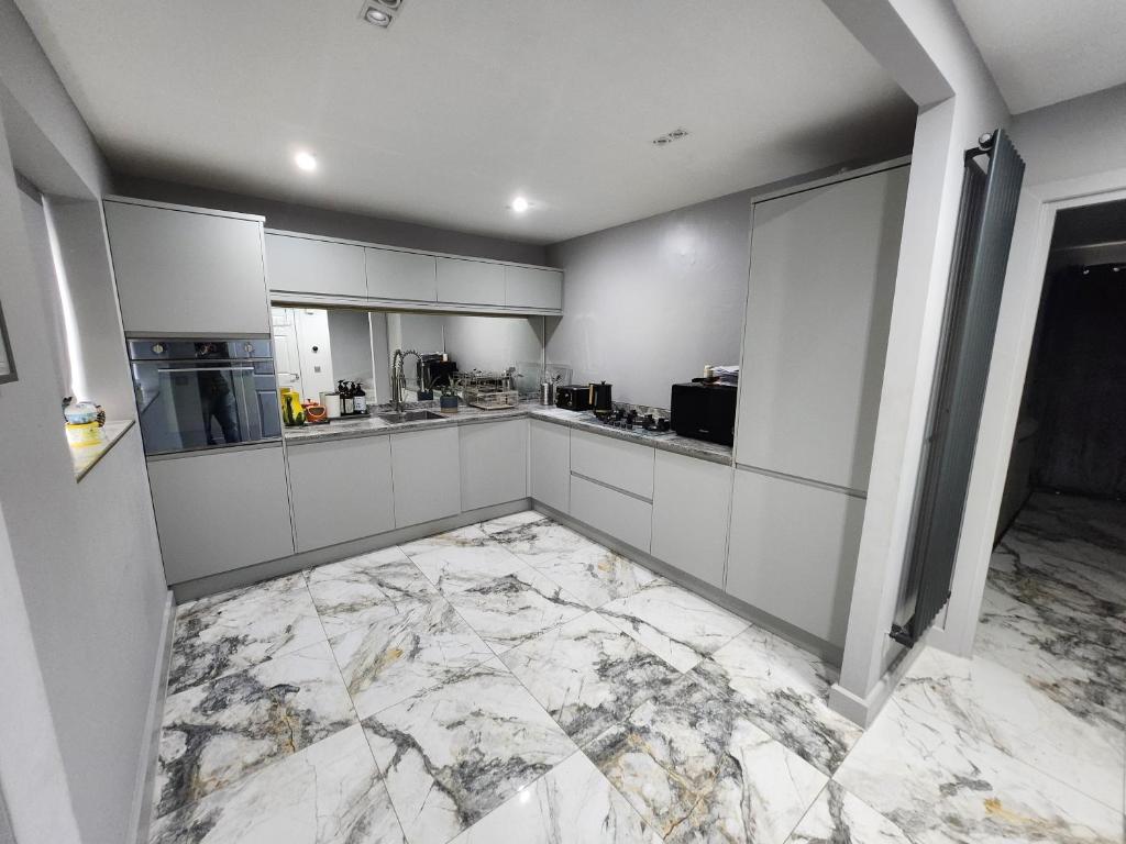 a large white kitchen with marble flooring at Sixty Nines in Dallington