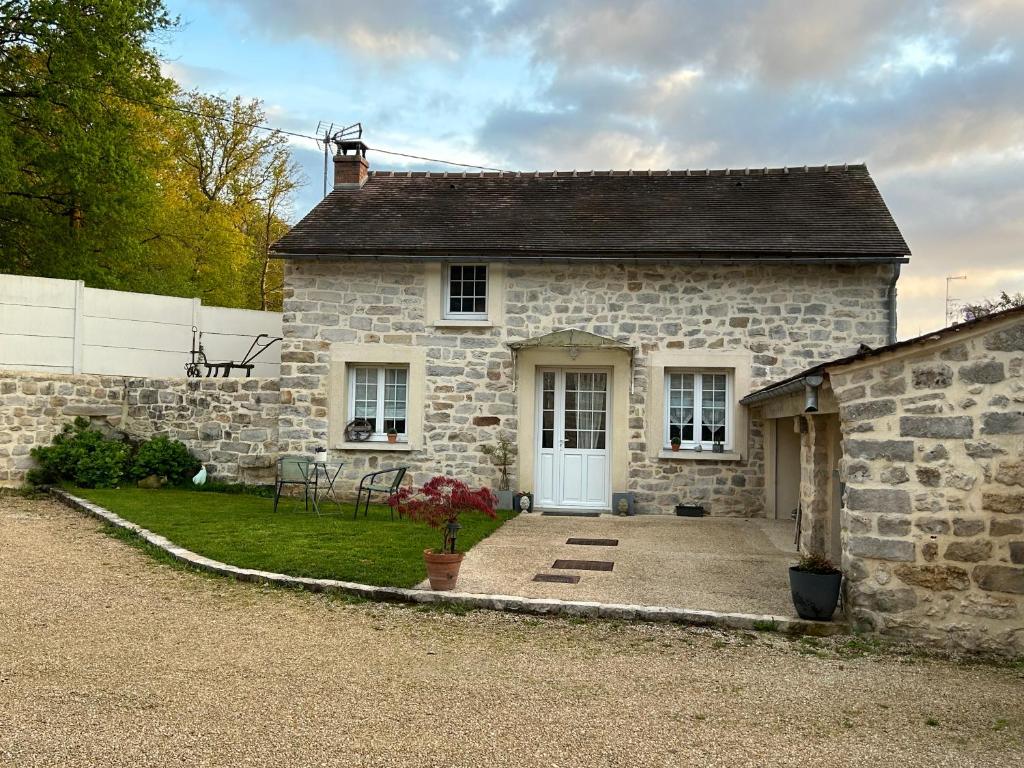 une maison en pierre avec une porte blanche et une cour dans l'établissement Charmante petite maison en pierre, à Boutigny-sur-Essonnes