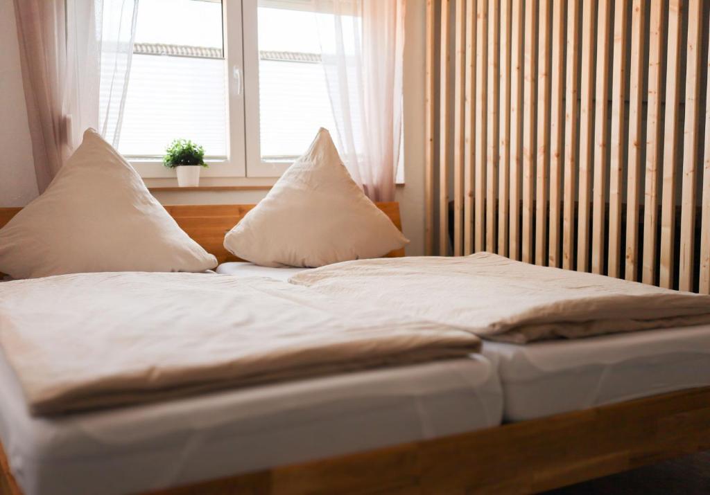 1 cama con sábanas y almohadas blancas frente a una ventana en Ferienwohnung zum Alten Fachwerk en Melsungen