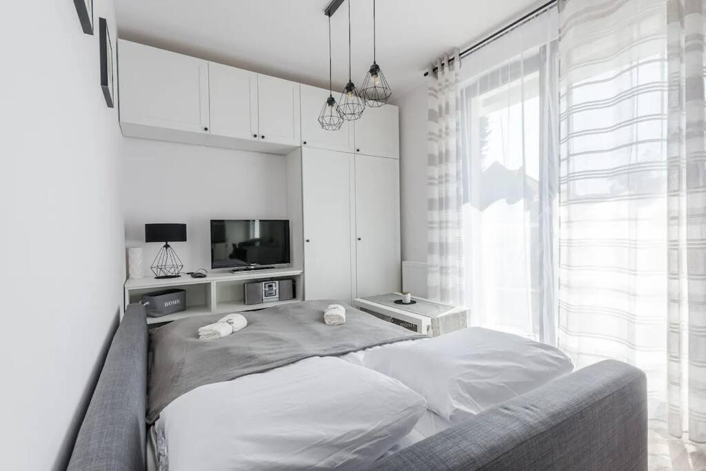 a white bedroom with a bed and a tv at GA Gdansk&Kollotaja in Gdańsk