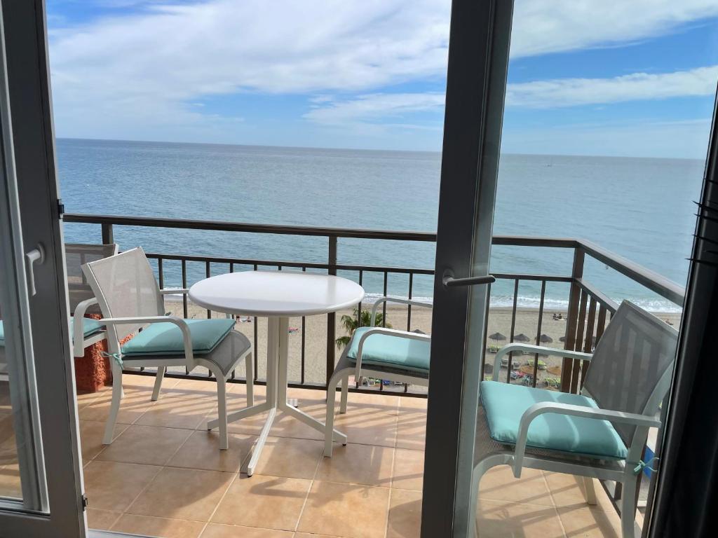 einen Balkon mit einem Tisch, Stühlen und Meerblick in der Unterkunft Beachfront Fuengirola Dreamin in Fuengirola