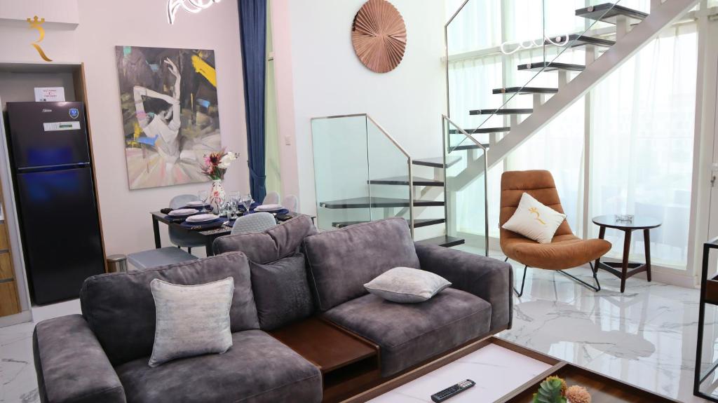 a living room with a couch and a staircase at Duplex 2BR Delight - Masdar City in Abu Dhabi