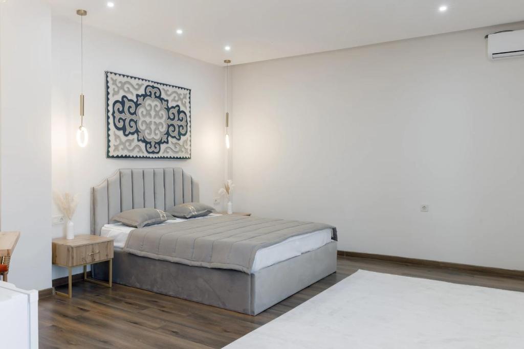Tumar Hansa Ethno Hotel في أستانا: غرفة نوم بيضاء مع سرير وطاولة