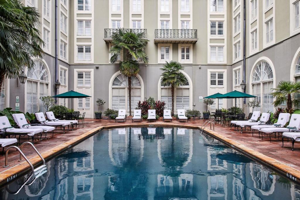 a pool in the courtyard of a hotel with chairs and umbrellas at Bourbon Orleans Hotel in New Orleans