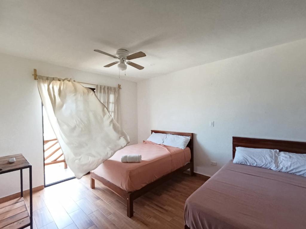 1 dormitorio con 2 camas y ventilador de techo en Secret Paradise Mahahual, en Mahahual