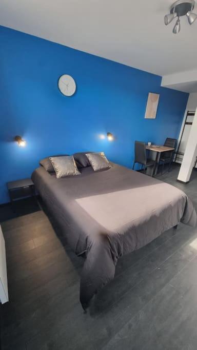 um quarto azul com uma cama com uma parede azul em L'Elégance 005 em Cambrai