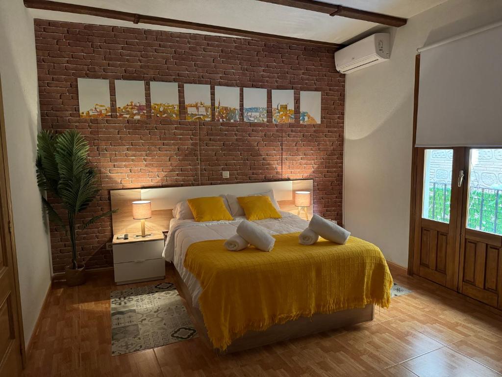 1 dormitorio con cama y pared de ladrillo en La Sal Home Toledo, en Toledo