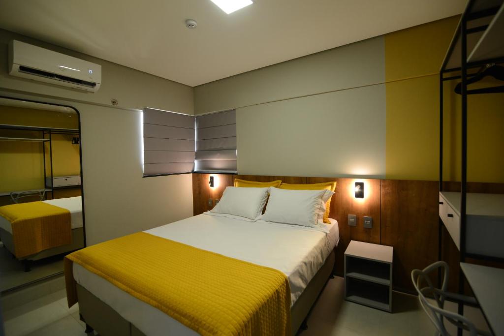 een kleine slaapkamer met een bed met een gele deken bij Brisas Flat Style in Cuiabá