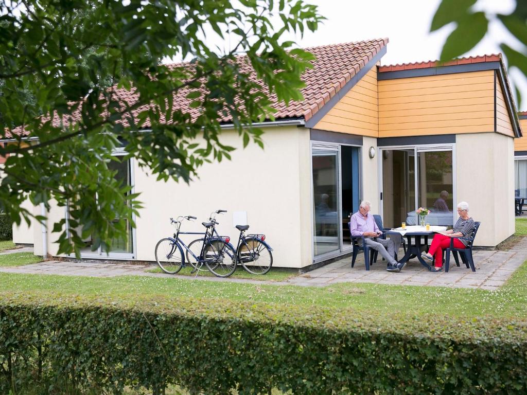 two people sitting at a table outside of a house at Nice holiday home with garden in Zevenhuizen