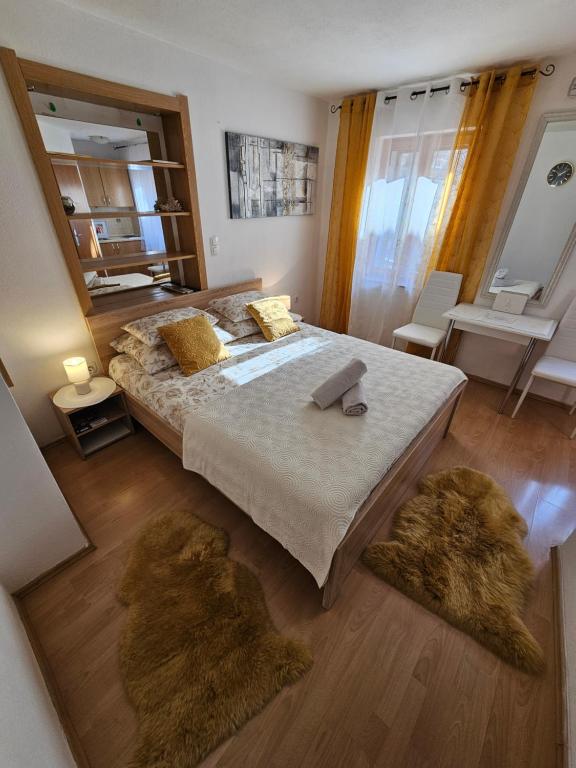 1 dormitorio con 1 cama grande y 2 alfombras en Studios Magnolia, en Trogir