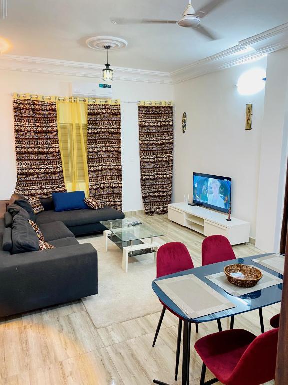 uma sala de estar com um sofá, uma mesa e uma televisão em Bel appartement entier 2 chambres em Cotonou