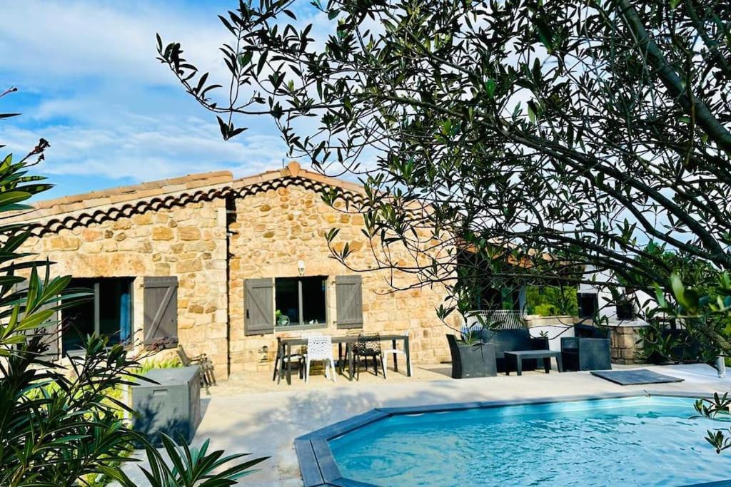 une maison en pierre avec une piscine en face de celle-ci dans l'établissement Gîte Le chant des mésanges 07260 Vernon, à Vernon