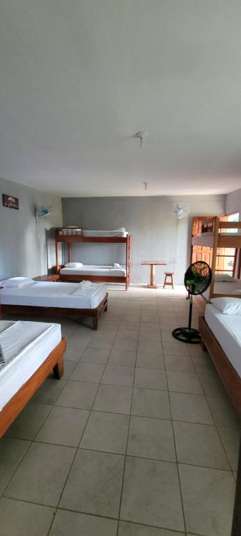 a room with three beds and a table in it at Hostal Xilotl in San José del Sur