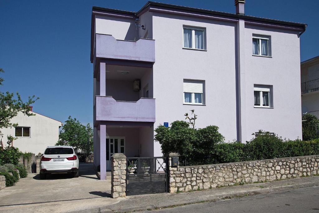 una casa blanca con un coche aparcado delante de ella en Apartments Branko, en Selce