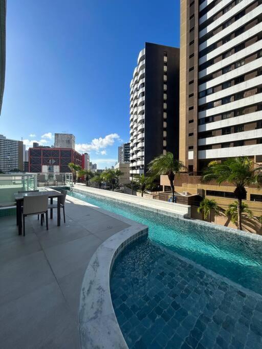 een zwembad met een tafel en stoelen op een gebouw bij Apartamento ITAIGARA in Salvador