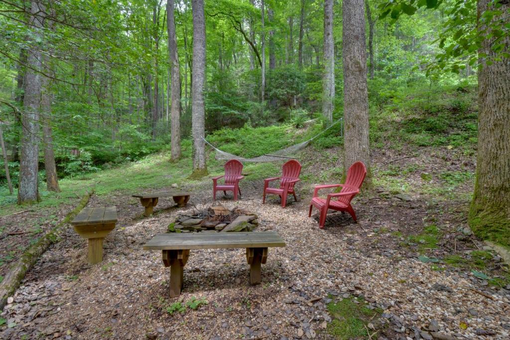 3 Stühle und eine Feuerstelle im Wald in der Unterkunft Cozy Blairsville Cabin 2 Mi to Vogel State Park! in Blairsville