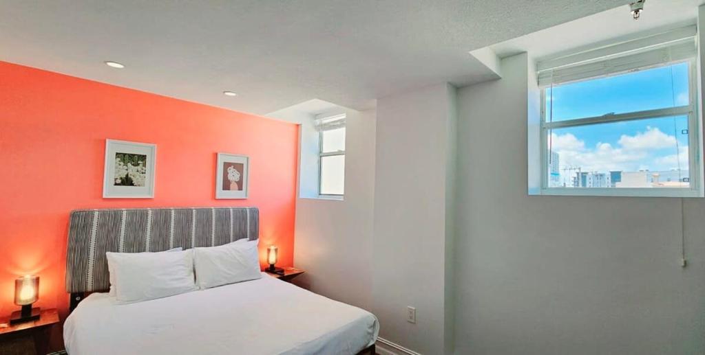 Un dormitorio con una pared de acento naranja y una cama en Walk to Everything From The Lofts Suite 307, en West Palm Beach