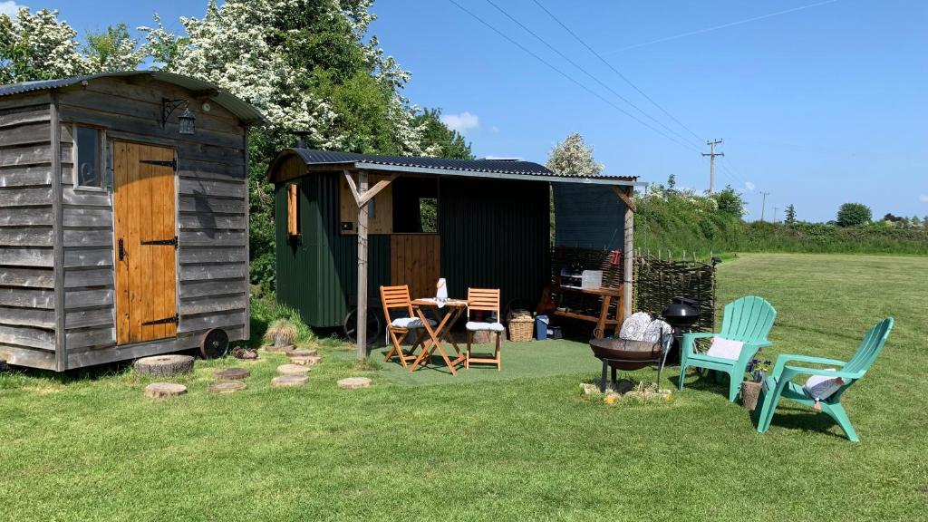 a wooden shed with chairs and a table in a yard at Willowdene shepherds hut in Oswestry